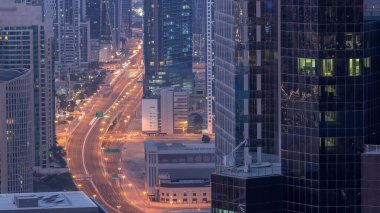 Hava görüntüsü Dubai 'deki yoğun kavşaklara gece gündüz geçiş zamanı. Gün doğmadan önce otoyolun her iki tarafına doğru giden arabalar var. İş bölgesi gökdelenleri