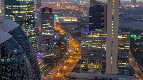 Skyline view of the high-rise buildings on curved road in Dubai aerial night to day transition timelapse, UAE. Office skyscrapers in International Financial Centre from above before sunrise