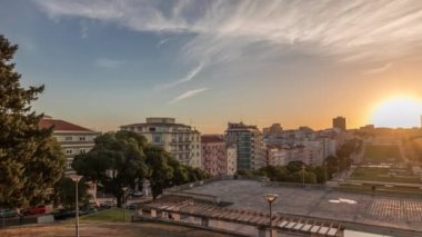 Panorama Alameda Dom Afonso Henriques 'deki çimlerin üzerinde gün batımını renkli binalar ve Aydınlık Çeşme hava saatleriyle gösteriyor. Lizbon, Portekiz 'de akşam gökyüzü ile yukarıdan görünüm