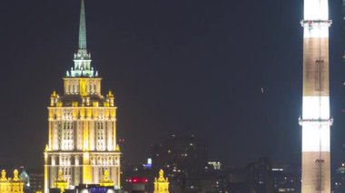 Evening view of the Hotel Ukraine and the Ostankin Tower between pipes from the observation deck on the Sparrow Hills in Moscow aerial timelapse. Night illumination