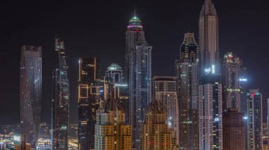 Dubai Marina 'nın gökdelenleri tüm gece boyunca parlayan ve yanıp sönen pencereli en yüksek konutlu binalar. JLT bölgesinden hava üst görünümü