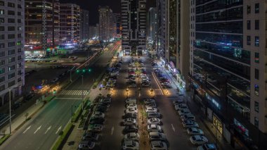 İkamet binaları ve Abu Dabi hava zaman çizelgesinin modern şehir mimarisi tüm gece boyunca, BAE. Otoparkta yukarıdan arabalara ve Birleşik Arap Emirlikleri 'nde gökdelenleri olan kulelere bak