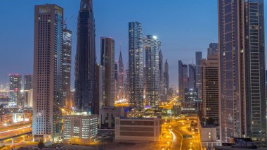 Dubai şehir merkezi ve finans bölgesindeki caddelerde trafiği olan gelecekçi kuleler ve gökdelenler. Şehir silueti gece gündüz gökyüzü geçiş zamanı gün doğumundan önce.
