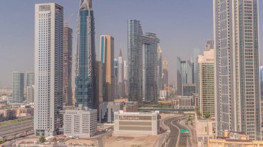 Tüm gün boyunca Dubai şehir merkezinde ve finans bölgesinde caddelerde trafik olan fütürist kuleler ve gökdelenler. Şehir silüeti, gölgelerle birlikte gün batımına kadar hızla hareket ediyor.