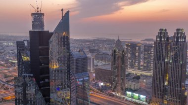 Dubai 'deki Sheikh Zayed Yolu' ndaki yüksek binalar. Gündüzden geceye geçiş zamanı, BAE. Uluslararası finans bölgesindeki gökdelenler. Arka planda evler ve villalar var.