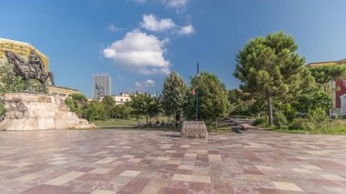 Arnavutluk 'un Tiran kentinin ana meydanında Skanderbeg anıtı ve Ethem Bey camisini gösteren panorama. Parktaki yeşil ağaçlar ve etraftaki gökdelenler