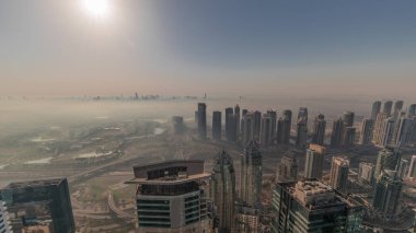 Dubai Marina Panoraması 'nda güneş doğarken JLT gökdelenleri ve golf sahası, Dubai, Birleşik Arap Emirlikleri. Yukarıdan hava manzarası sisli bir sabah. Turuncu gökyüzü ile şehir silueti