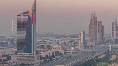 Dubai 'deki Sheikh Zayed Yolu' nun zaman ayarlı hava görüntüsü. Gün batımında metro istasyonlu bir otoyolda gökdelenler ve trafik
