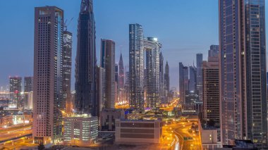 Dubai şehir merkezi ve finans bölgesindeki caddelerde trafiği olan gelecekçi kuleler ve gökdelenler. Şehir silueti gece gündüz gökyüzü geçiş zamanı gün doğumundan önce.