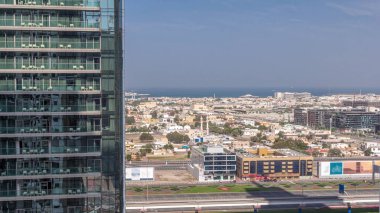 Dubai Şehir Yürüyüşü 'nün hava görüntüsü hızla hareket eden gölgelerle gökdelen zaman aralığının arkasına bakıyor. Avrupa tarzı yaratılmış düşük katlı binalar ve villalar. Şeyh zayed yolu ve metro trafiği