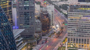 Finansal bölgedeki Al Saada caddesindeki trafiğin hava görüntüsü Dubai, BAE 'deki gece geçiş zamanı. Aydınlatılmış gökdelenler ve yukarıdaki ofis kulelerinde parlayan pencereler.