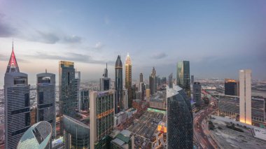 Dubai 'deki Sheikh Zayed Yolu' ndaki gökdelenlerin gökyüzü panoramik görüntüsü. Gün batımından gece geçiş zamanına, BAE. Uluslararası Finans Merkezi 'nde yukarıdan aydınlatılmış gökdelenler