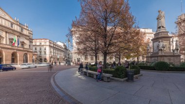 Panorama showing theater La Scala timelapse and a small park opposite to historic building with a monument to Leonardo da Vinci and his students. People walking around and sitting on a bench