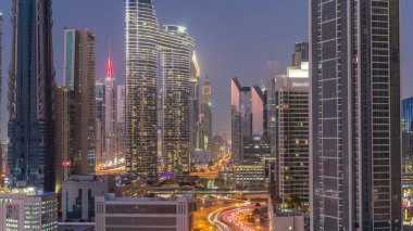 Günbatımından sonra Dubai şehir merkezinde ve finans bölgesinde caddelerde trafik olan fütürist kuleler ve gökdelenler. Şehir silueti gökyüzü günden geceye geçiş zamanı yukarıdan