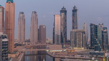 Dubai İşletme Koyu 'nun gökdelenleri ve su kanalı antenleri olan şehir manzarası. Gece gündüz geçiş zamanı. Gündoğumundan önce rıhtımda konut ve ofis kuleleri olan modern gökyüzü.