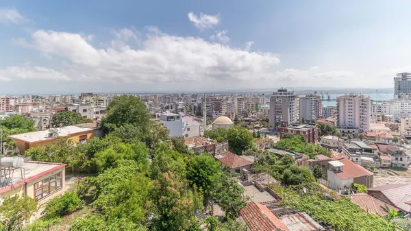 Panorama, Arnavutluk 'un Durres limanı ve şehir merkezinin (eski kent) hava manzarasını gösteriyor. Gökyüzünde bulutlar olan, kırmızı çatıları ve yeşil ağaçları olan birçok ev.