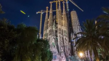 İspanya 'nın Barcelona kentindeki Aydınlanmış Sagrada Familia' dan Timelapse Hyperlapse. Spires ve Crane 'ler Skyline Etch, parktan büyüleyici bir manzara Büyüleyici bir gece görüşü sunuyor