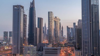 Dubai şehir merkezi ve finans bölgesindeki caddelerde trafiği olan gelecekçi kuleler ve gökdelenler. Şehir silueti gece gündüz gökyüzü geçiş zamanı gün doğumundan önce.