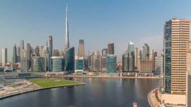 Dubai Business Bay ve şehir merkezinin havadan görüntüsü. Kanal zamanındaki çeşitli gökdelenler ve kuleler. Vinçleri olan bir inşaat alanı. Gökyüzündeki bulutlar