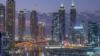 Dubai İşletme Koyu 'nun gökdelenleri ve su kanalı havadan akşama geçiş zamanı olan şehir manzarası. Günbatımından sonra rıhtımda konut ve ofis kuleleri olan modern gökyüzü