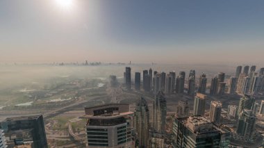Dubai Marina Panoraması 'nda güneş doğarken JLT gökdelenleri ve golf sahası, Dubai, Birleşik Arap Emirlikleri. Yukarıdan hava manzarası sisli bir sabah. Turuncu gökyüzü ile şehir silueti
