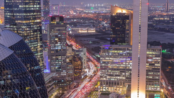 Skyline view of the high-rise buildings on busy road in Dubai aerial day to night transition timelapse, UAE. Illuminated office skyscrapers in International Financial Centre from above