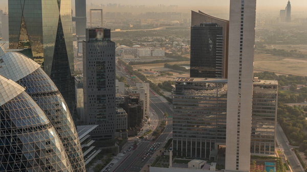 Skyline view of the high-rise buildings around highway road in Dubai aerial timelapse during sunrise, UAE. Skyscrapers in International Financial Centre from above early morning