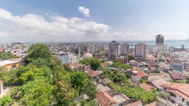 Panorama, Arnavutluk 'un Durres limanı ve şehir merkezinin (eski kent) hava manzarasını gösteriyor. Gökyüzünde bulutlar olan, kırmızı çatıları ve yeşil ağaçları olan birçok ev.