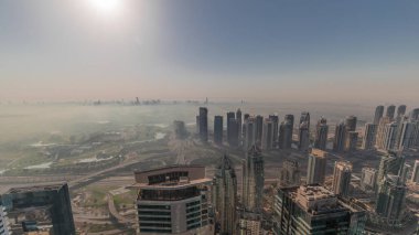 Dubai Marina Panoraması 'nda güneş doğarken JLT gökdelenleri ve golf sahası, Dubai, Birleşik Arap Emirlikleri. Yukarıdan hava manzarası sisli bir sabah. Turuncu gökyüzü ile şehir silueti
