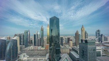 Şeyh Zayed yolundaki Dubai 'deki finans bölgesi iş merkezindeki fütüristik gökdelenlerin panoraması. Gün doğumu ve uzun gölgelerle aydınlık kuleleri olan gökyüzü manzarası