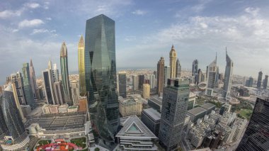Dubai 'deki finans bölgesi iş merkezindeki gelecekçi gökdelenlerin panoraması. Gece gündüz yol trafiği geçiş zamanı. Güneş doğarken yukarıdan aydınlatma kuleleri ile gökyüzü görüntüsü