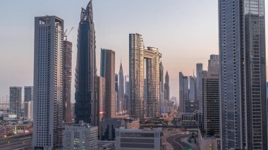 Dubai şehir merkezi ve finans bölgesindeki caddelerde trafiği olan gelecekçi kuleler ve gökdelenler. Şehir silueti gece gündüz gökyüzü geçiş zamanı gün doğumundan önce.