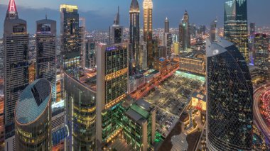 Dubai 'deki Sheikh Zayed Yolu' ndaki gökdelenlerin ufuk çizgisi manzarası. Günbegün hava geçiş zamanı, BAE. Aydınlatılmış gökdelenler ve yukarıdan Uluslararası Finans Merkezi 'ne park