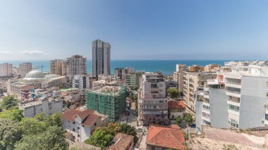 Panorama, Arnavutluk 'un Durres limanı ve şehir merkezinin (eski kent) hava manzarasını gösteriyor. Gökyüzünde bulutlar olan yeşil ağaçlı birçok ev