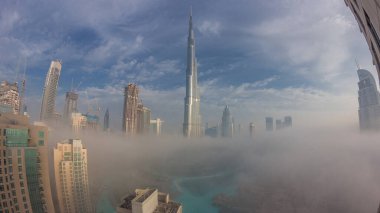 Sabahın erken saatlerinde, sis gecesinden gündüze geçiş zamanlarında Dubai şehrinin hava görüntüsü. Gökdelenleri ve kuleleri olan gelecekçi şehir gökdelenleri ve gökdelenleri yukarıdan gün doğumunda