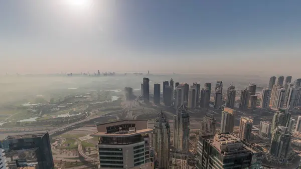 Dubai Marina Panoraması 'nda güneş doğarken JLT gökdelenleri ve golf sahası, Dubai, Birleşik Arap Emirlikleri. Yukarıdan hava manzarası sisli bir sabah. Turuncu gökyüzü ile şehir silueti