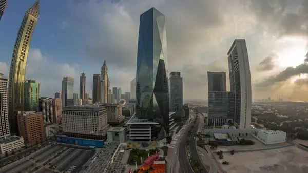 Panorama of Dubai International Financial district. Aerial view of business office towers during sunrise. Illuminated skyscrapers with hotels and shopping malls near downtown