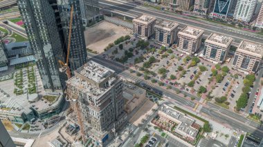 Dubai 'deki Sheikh Zayed Yolu' ndaki vinçleri ve binaları olan inşaat alanı. Finans bölgesinde gökdelenler, hareket eden uzun gölgeler. Bir sürü arabası olan park yeri.