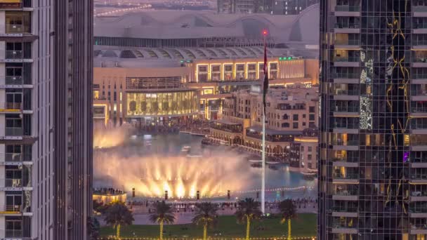 从空中俯瞰位于市区的迪拜喷泉 在购物中心旁边的公园里挂着棕榈和国旗 以及从南到南的过渡时间 阿联酋 日落后在两幢摩天大楼之间看到的景象 — 图库视频影像
