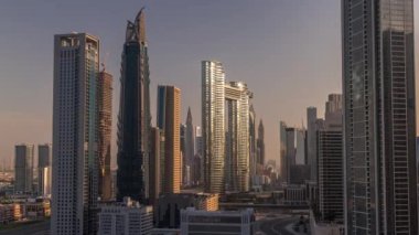 Dubai şehir merkezi ve finans bölgesinde caddelerde trafiği olan fütürist kuleler ve gökdelenler. Şehir silueti, gün doğumunda havadan sabah saatleri. Sıcak ışık ve güneş camdan yansıyor.