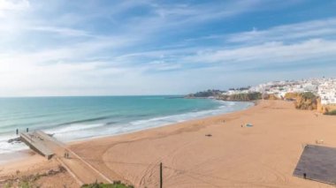 Panorama Albufeira Timelapse şehrinde geniş kumlu sahil ve Atlantik okyanusunu gösteriyor. Uçurumun tepesindeki beyaz evler. Yukarıdan hava görüntüsü. Mavi gökyüzündeki bulutlar. Algarve, Portekiz