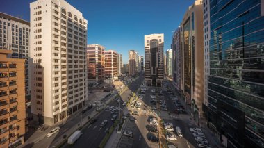 İkamet binaları ve Abu Dabi hava saatinin modern şehir mimarisi tüm gece boyunca gün doğumuna kadar, BAE. Otoparkta yukarıdan arabalara ve gökdelenli kulelerin uzun gölgelerine bak