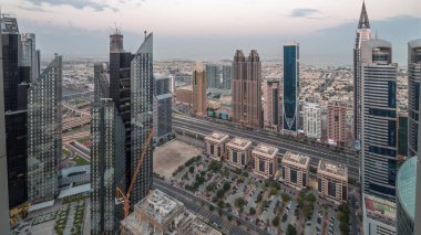 Dubai 'deki Sheikh Zayed Yolu' ndaki yüksek binalar gece gündüz panoramik zaman geçişi, BAE. Finans bölgesindeki gökdelenler. Arka planda evler ve villalar var.