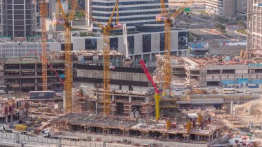 Çalışan vinçleri olan büyük bir inşaat alanı. Business Bay, Dubai 'deki büyük yerleşim ve ofis alanının en iyi hava görüntüsü. Takviyeli üniformalı işçiler
