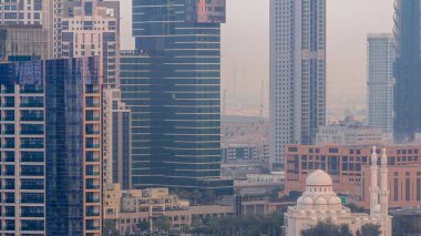 Bay Bulvarı yakınlarındaki yeni beyaz cami. Alışveriş merkezi Business Bay hava sahasında gökdelenlerle çevrili. Gün doğumundan önce geçiş zamanı. Otoparkın yanındaki yolda trafik vardı.