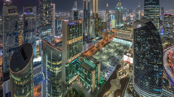 Skyline view of the high-rise buildings on Sheikh Zayed Road in Dubai aerial day to night transition timelapse, UAE. Illuminated skyscrapers and parking in International Financial Centre from above