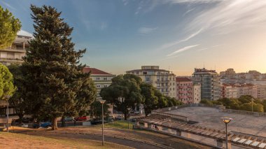 Panorama Alameda Dom Afonso Henriques 'deki çimlerin üzerinde gün batımını renkli binalar ve Aydınlık Çeşme hava saatleriyle gösteriyor. Lizbon, Portekiz 'de akşam gökyüzü ile yukarıdan görünüm