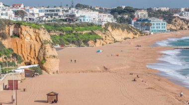 Geniş kumlu sahil ve Albufeira zamanındaki Atlantik Okyanusu. Uçurumun tepesindeki beyaz evler. Yukarıdan hava görüntüsü. Algarve, Portekiz