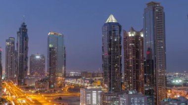 Business Bay semtinin ufuk çizgisi gece gündüz modern mimari geçiş zamanı yukarıdan. Güneş doğmadan önce Dubai gökdelenlerinin ve ana karayolu yakınlarındaki kulelerin havadan görüntüsü. Yol ayrımında trafik