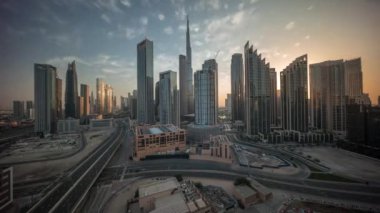 Gün doğumunda Dubai şehir merkezinin gökyüzü görüntüsü ve birçok zaman kulesi. Gökdelenler ve yüksek binalar arasındaki güneş ışınları, BAE. Akıllı kentsel şehirde iş alanı.
